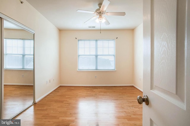 empty room with ceiling fan, visible vents, a wealth of natural light, and wood finished floors