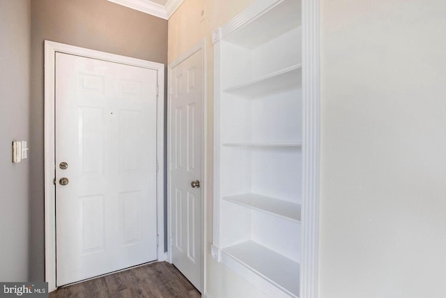 doorway with crown molding, dark wood-style flooring, and built in shelves