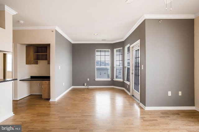 interior space with baseboards, ornamental molding, and light wood-style flooring
