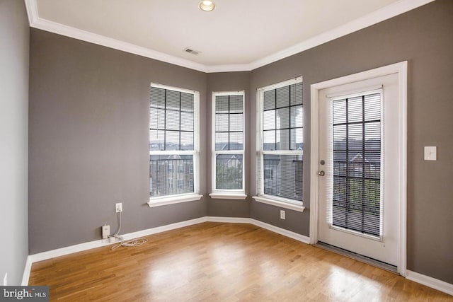doorway to outside with visible vents, ornamental molding, baseboards, and wood finished floors