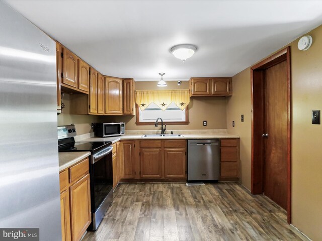 kitchen with light countertops, dark wood-style flooring, appliances with stainless steel finishes, and a sink