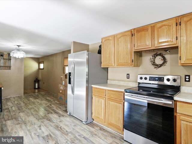 kitchen with light brown cabinets, light countertops, light wood-style floors, a chandelier, and stainless steel appliances