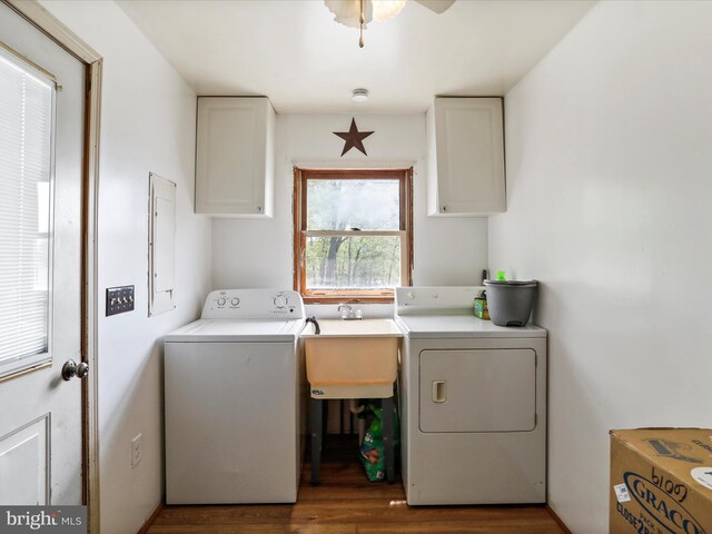 laundry area with cabinet space, a sink, a ceiling fan, wood finished floors, and washing machine and dryer