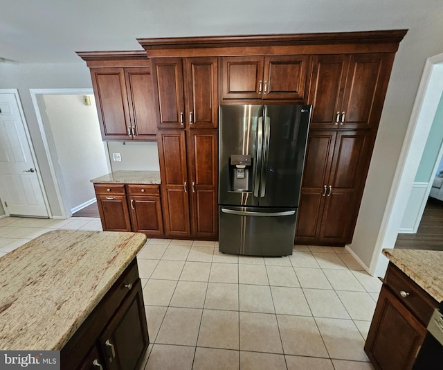 kitchen with stainless steel refrigerator with ice dispenser, baseboards, light stone counters, and light tile patterned flooring