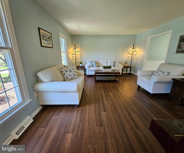 living room featuring a wealth of natural light, dark wood-type flooring, and visible vents