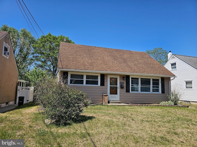 view of front of home with roof with shingles, fence, a chimney, and a front lawn
