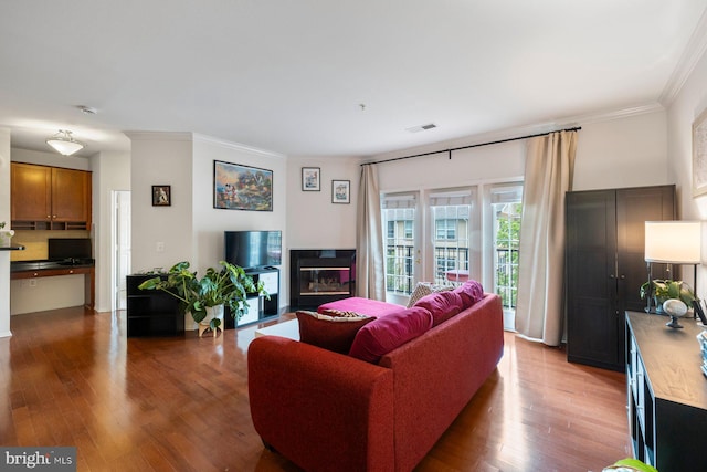 living area featuring visible vents, ornamental molding, and wood finished floors
