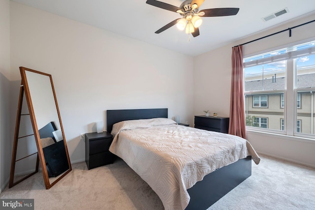 bedroom featuring baseboards, visible vents, light carpet, and ceiling fan