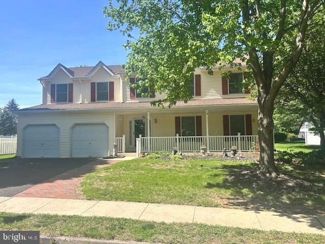 view of front of house with covered porch, an attached garage, a front yard, and aphalt driveway