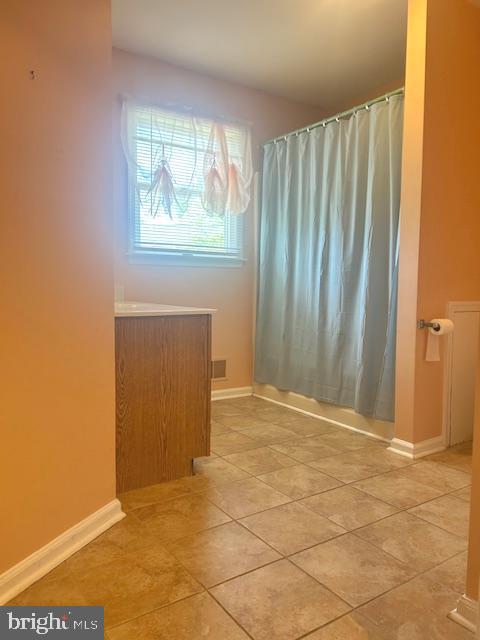 unfurnished room featuring baseboards and light tile patterned floors