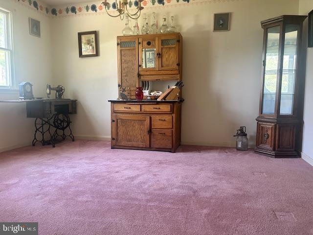 interior space featuring light colored carpet, baseboards, and a notable chandelier