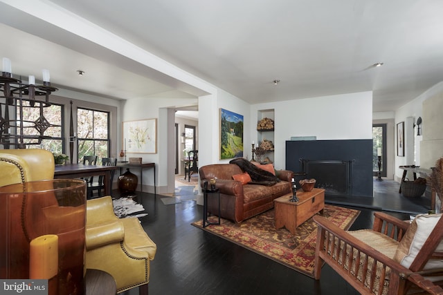 living area with wood finished floors, a fireplace with raised hearth, and baseboards