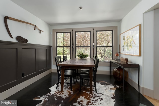 dining space with a wainscoted wall and dark wood-style flooring