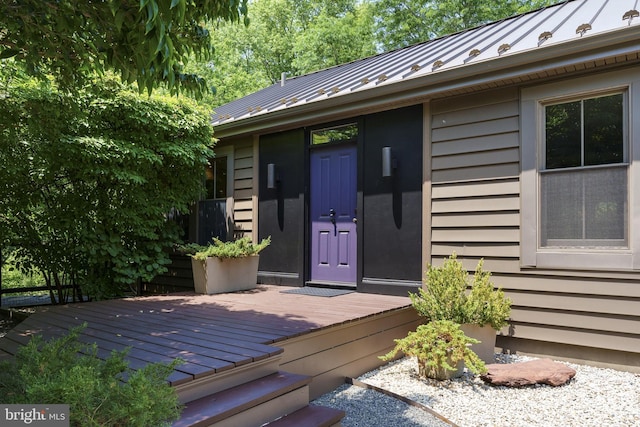 entrance to property with a standing seam roof, a deck, and metal roof