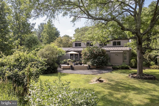 rear view of house with a standing seam roof, outdoor lounge area, a lawn, and metal roof