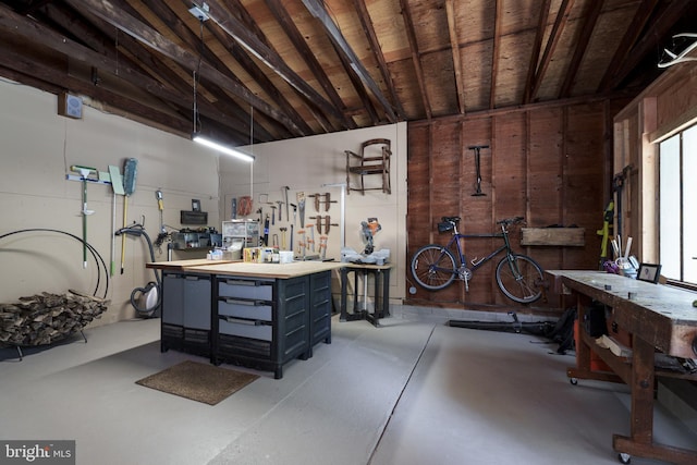 miscellaneous room with a workshop area, finished concrete flooring, vaulted ceiling, wooden walls, and wooden ceiling