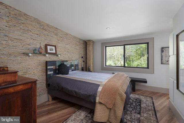 bedroom with wood finished floors and lofted ceiling
