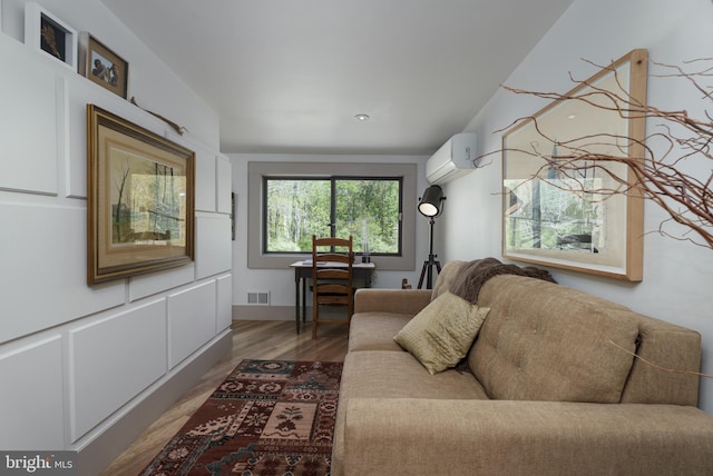 living area with a wall mounted air conditioner and light wood-style floors