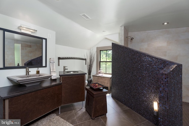 bathroom featuring a walk in shower, two vanities, tile patterned flooring, and vaulted ceiling