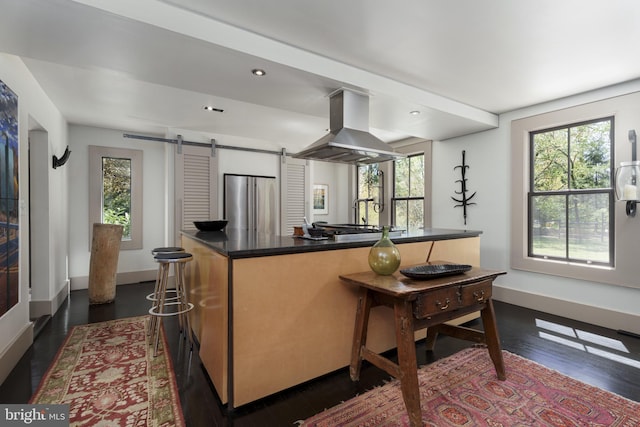 kitchen featuring island exhaust hood, a barn door, plenty of natural light, freestanding refrigerator, and recessed lighting