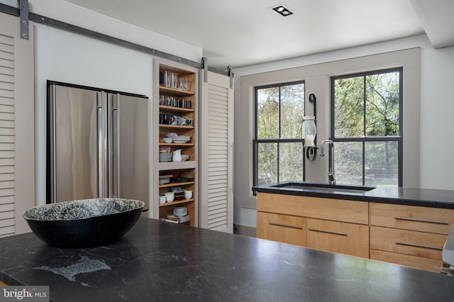 kitchen featuring a barn door, a sink, open shelves, and light brown cabinets