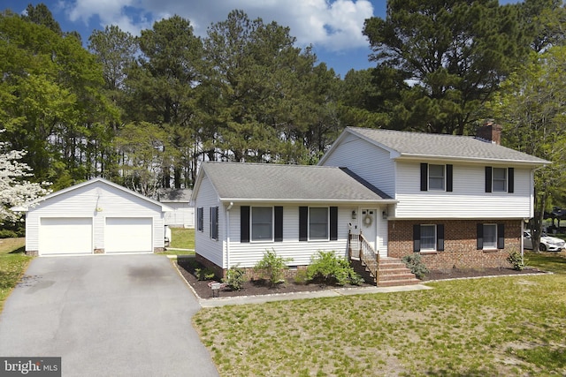 tri-level home featuring a detached garage, an outdoor structure, a chimney, and a front yard