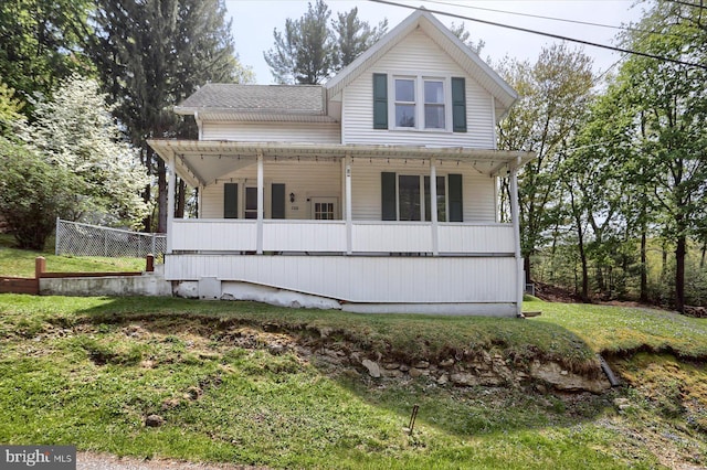 view of front of property featuring a porch, roof with shingles, and a front lawn