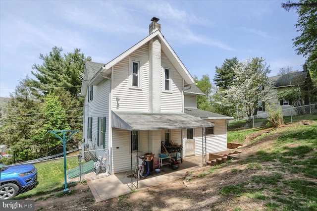 rear view of house with a shingled roof, a gate, fence, and a chimney