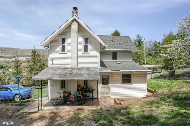 back of property featuring fence, a shingled roof, and a chimney