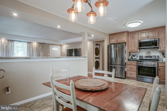 20 Aspen Dr, Pennsville, NJ 08070 - kitchen featuring stacked washer / dryer, appliances with stainless steel finishes, tasteful backsplash, baseboards, and a notable chandelier