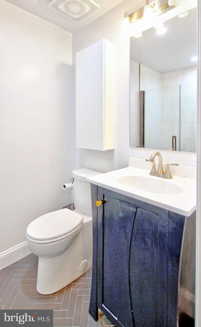 bathroom featuring brick floor, vanity, toilet, baseboards, and visible vents