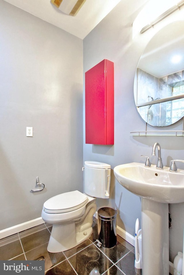 bathroom with a sink, baseboards, tile patterned flooring, and toilet