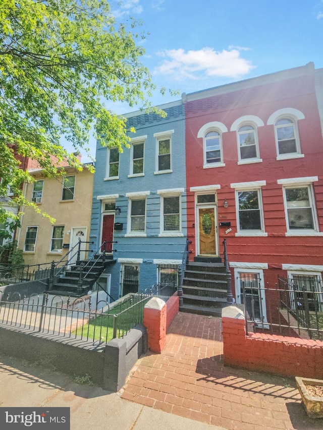 multi unit property featuring entry steps, a fenced front yard, and brick siding