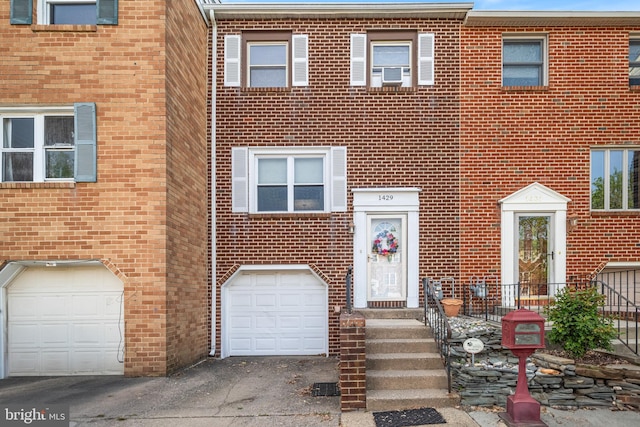 view of property featuring brick siding, cooling unit, and a garage