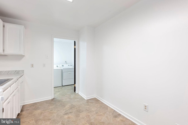 3403 Toone St, Baltimore, MD 21224 - kitchen with separate washer and dryer, white cabinets, light countertops, and baseboards