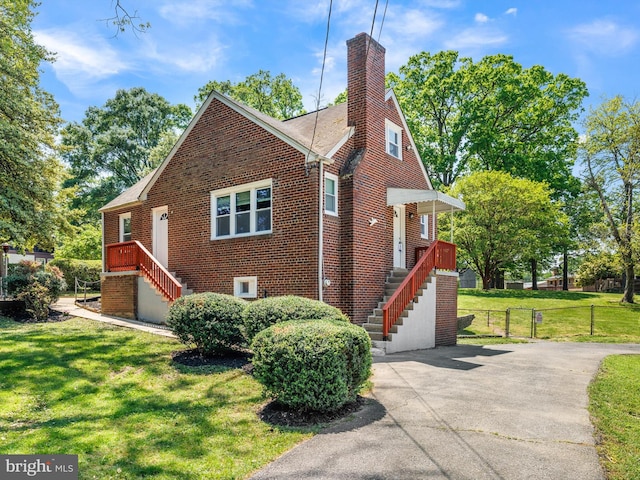 view of side of home with brick siding, fence, a yard, and a chimney