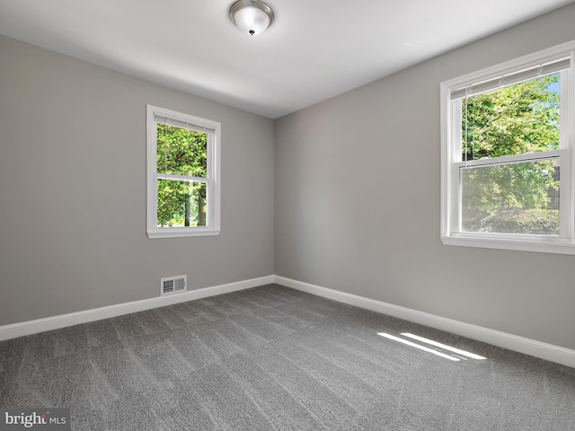 unfurnished room featuring baseboards, visible vents, and carpet