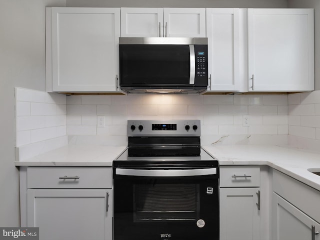 kitchen featuring white cabinets, light stone counters, electric stove, stainless steel microwave, and decorative backsplash
