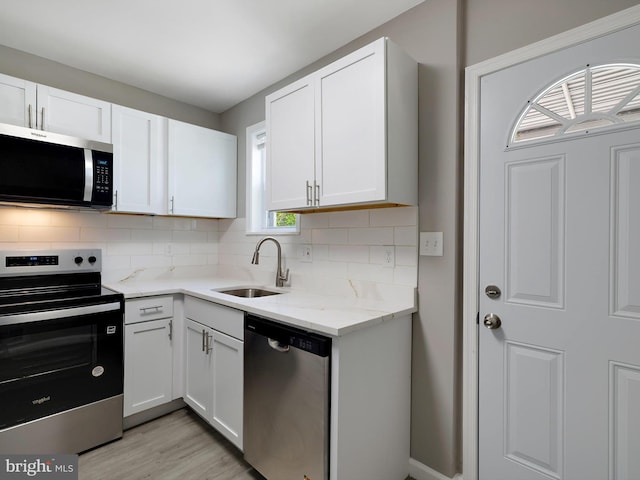 kitchen featuring a sink, appliances with stainless steel finishes, white cabinets, and backsplash