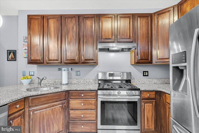 kitchen featuring exhaust hood, stainless steel appliances, light stone counters, and a sink