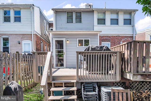 back of property featuring fence, cooling unit, a deck, and brick siding