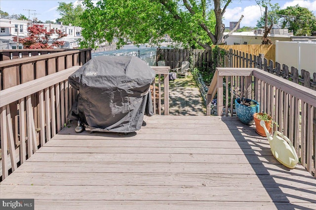 wooden terrace with a fenced backyard and area for grilling