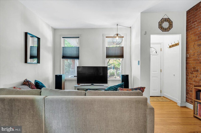 living area featuring brick wall and light wood-style flooring