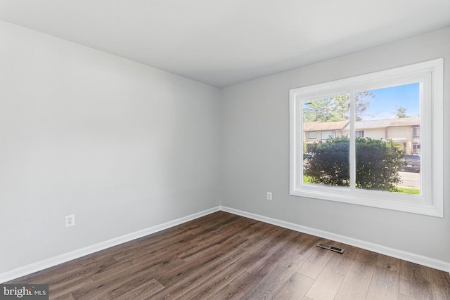 empty room with dark wood-type flooring and baseboards