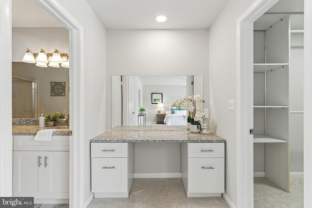 ensuite bathroom with an enclosed shower, vanity, and baseboards
