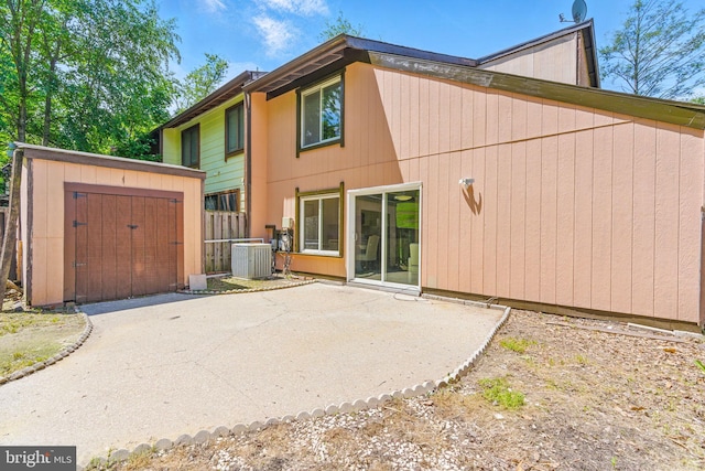 rear view of house with an outdoor structure, cooling unit, a patio, a shed, and fence