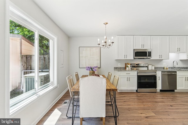 dining room with a chandelier, wood finished floors, and baseboards
