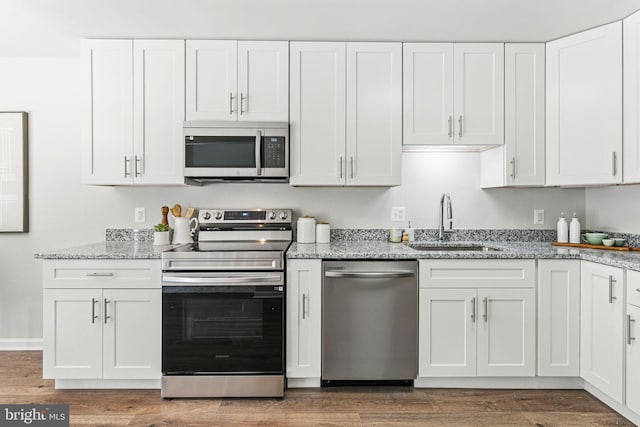 kitchen featuring appliances with stainless steel finishes, a sink, white cabinets, and dark wood-style floors