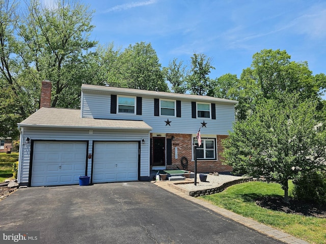 traditional-style house featuring brick siding, a garage, a chimney, and aphalt driveway