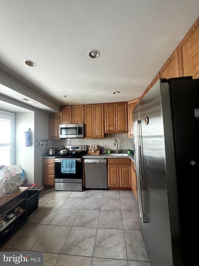 kitchen with brown cabinetry, visible vents, a sink, stainless steel appliances, and recessed lighting